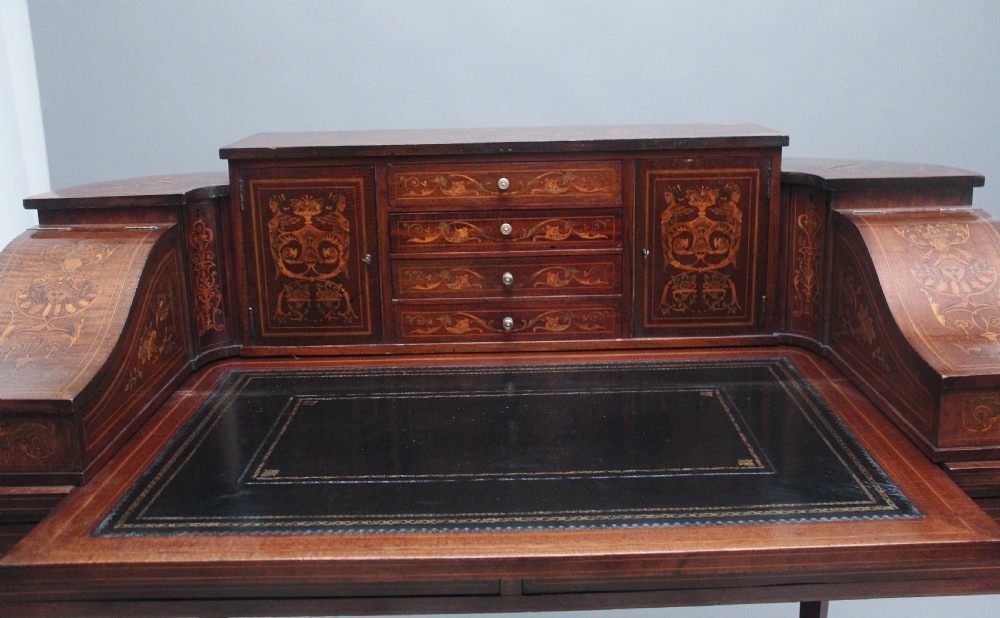 A pair of early 20th-century mahogany Carlton House desks with detailed satinwood marquetry inlay, stepped gallery drawers, and tapered legs. View XXIII