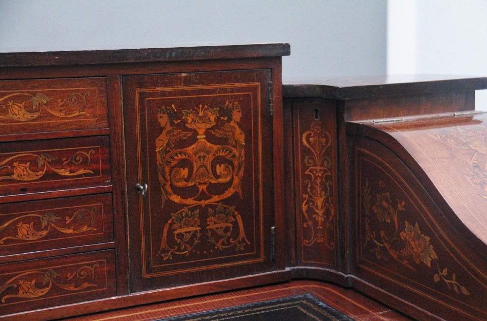 A pair of early 20th-century mahogany Carlton House desks with detailed satinwood marquetry inlay, stepped gallery drawers, and tapered legs. View XXIV