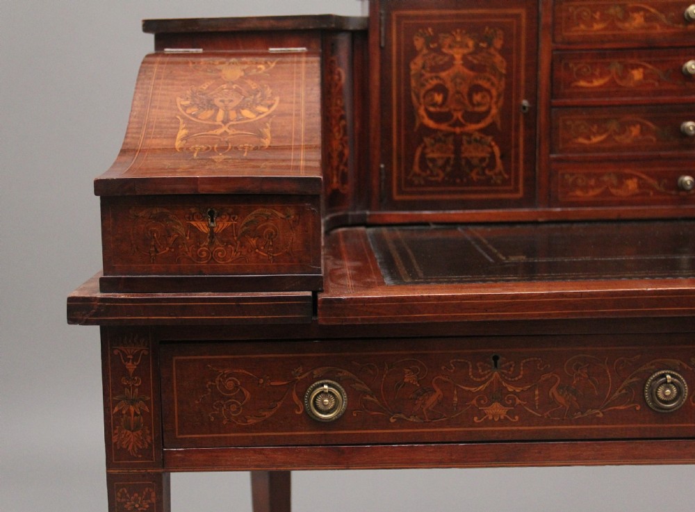 A pair of early 20th-century mahogany Carlton House desks with detailed satinwood marquetry inlay, stepped gallery drawers, and tapered legs. View XXV