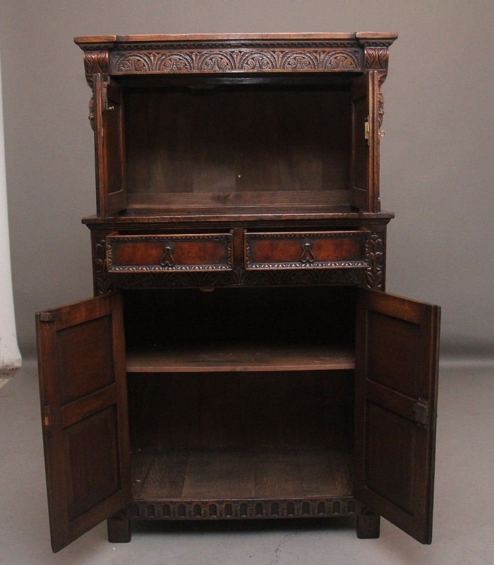 A carved dark oak court cupboard featuring arcaded door panels, turned bulbous supports, and geometric inlay details. View II
