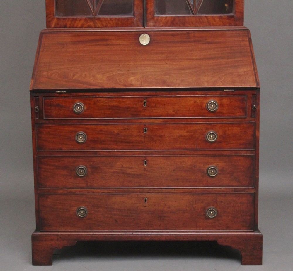 An early nineteenth-century mahogany bureau bookcase featuring a swan-neck pediment, diamond astragal glazed upper doors, a slant-front writing flap, and four graduated drawers. View V
