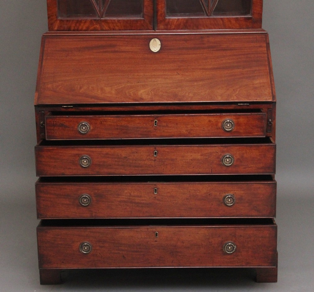 An early nineteenth-century mahogany bureau bookcase featuring a swan-neck pediment, diamond astragal glazed upper doors, a slant-front writing flap, and four graduated drawers. View VI