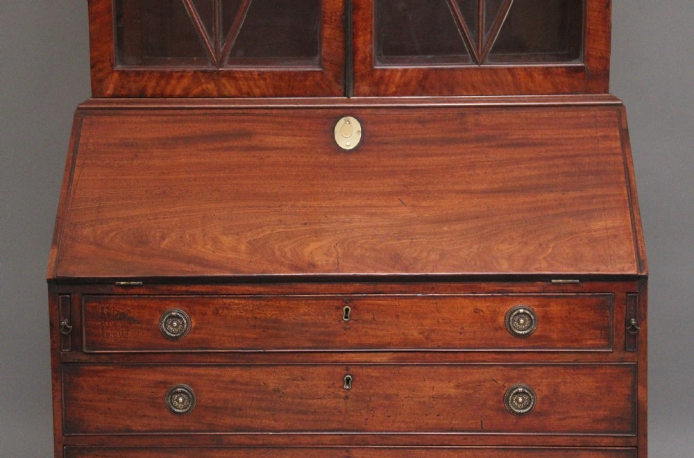 An early nineteenth-century mahogany bureau bookcase featuring a swan-neck pediment, diamond astragal glazed upper doors, a slant-front writing flap, and four graduated drawers. View VII