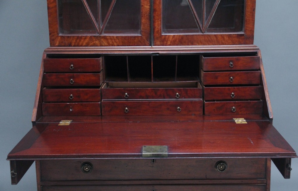 An early nineteenth-century mahogany bureau bookcase featuring a swan-neck pediment, diamond astragal glazed upper doors, a slant-front writing flap, and four graduated drawers. View IX