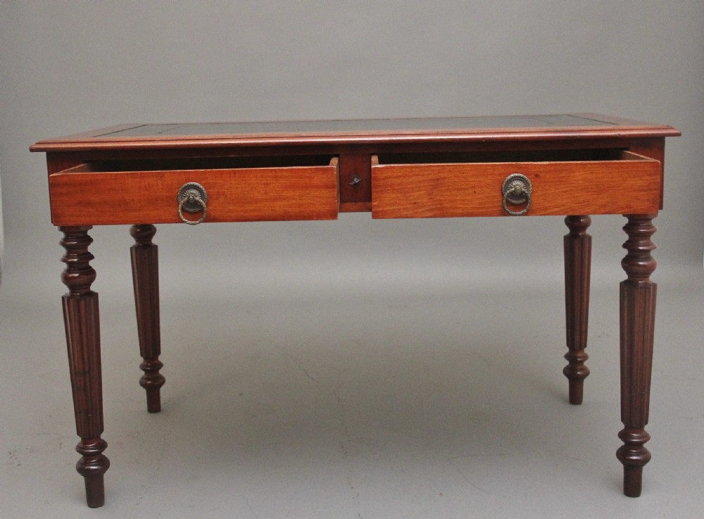 A 19th-century mahogany writing table featuring two frieze drawers with brass ring drop handles, supported by four turned and reeded legs. View II