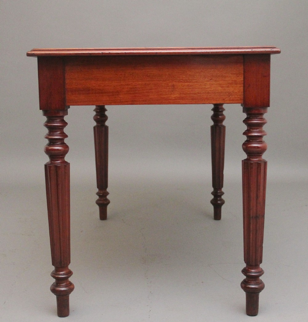 A 19th-century mahogany writing table featuring two frieze drawers with brass ring drop handles, supported by four turned and reeded legs. View V