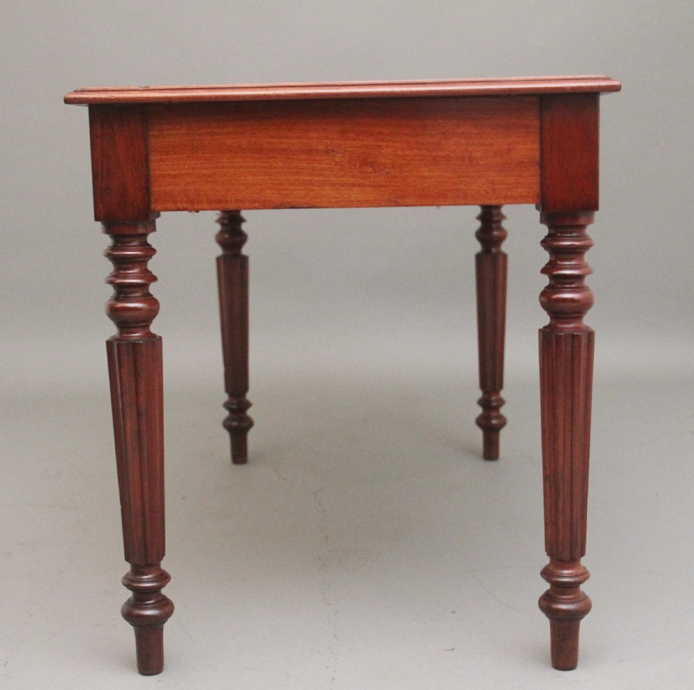 A 19th-century mahogany writing table featuring two frieze drawers with brass ring drop handles, supported by four turned and reeded legs. View VII