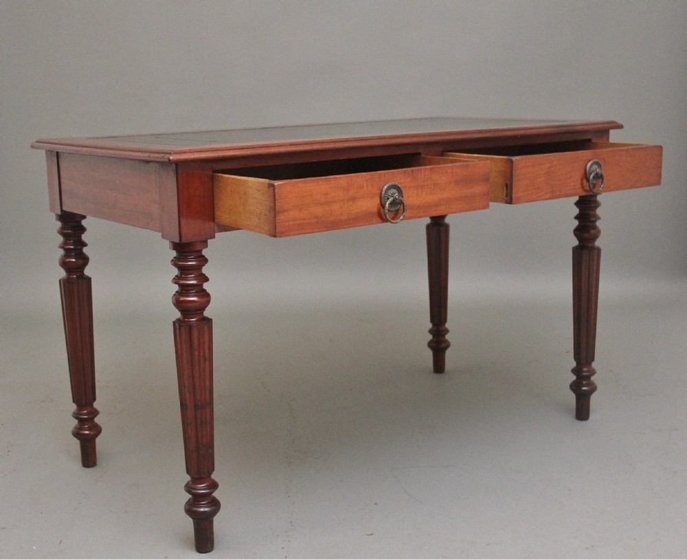 A 19th-century mahogany writing table featuring two frieze drawers with brass ring drop handles, supported by four turned and reeded legs. View VIII