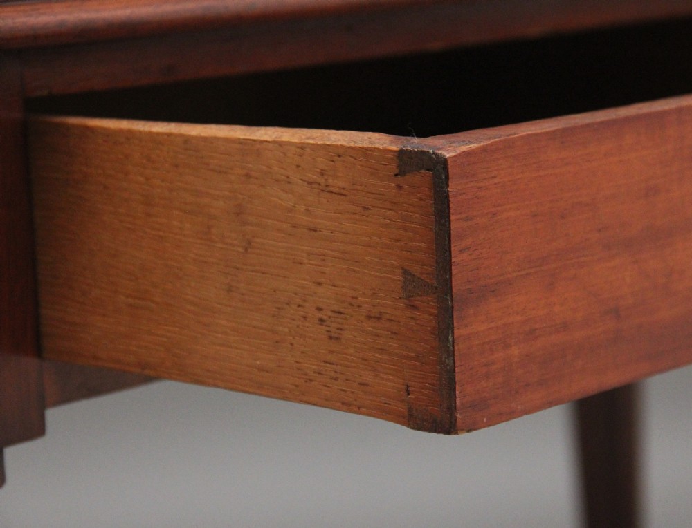 A 19th-century mahogany writing table featuring two frieze drawers with brass ring drop handles, supported by four turned and reeded legs. View X