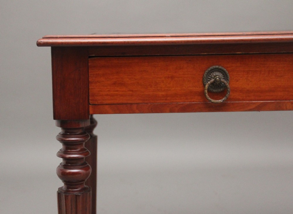 A 19th-century mahogany writing table featuring two frieze drawers with brass ring drop handles, supported by four turned and reeded legs. View XI
