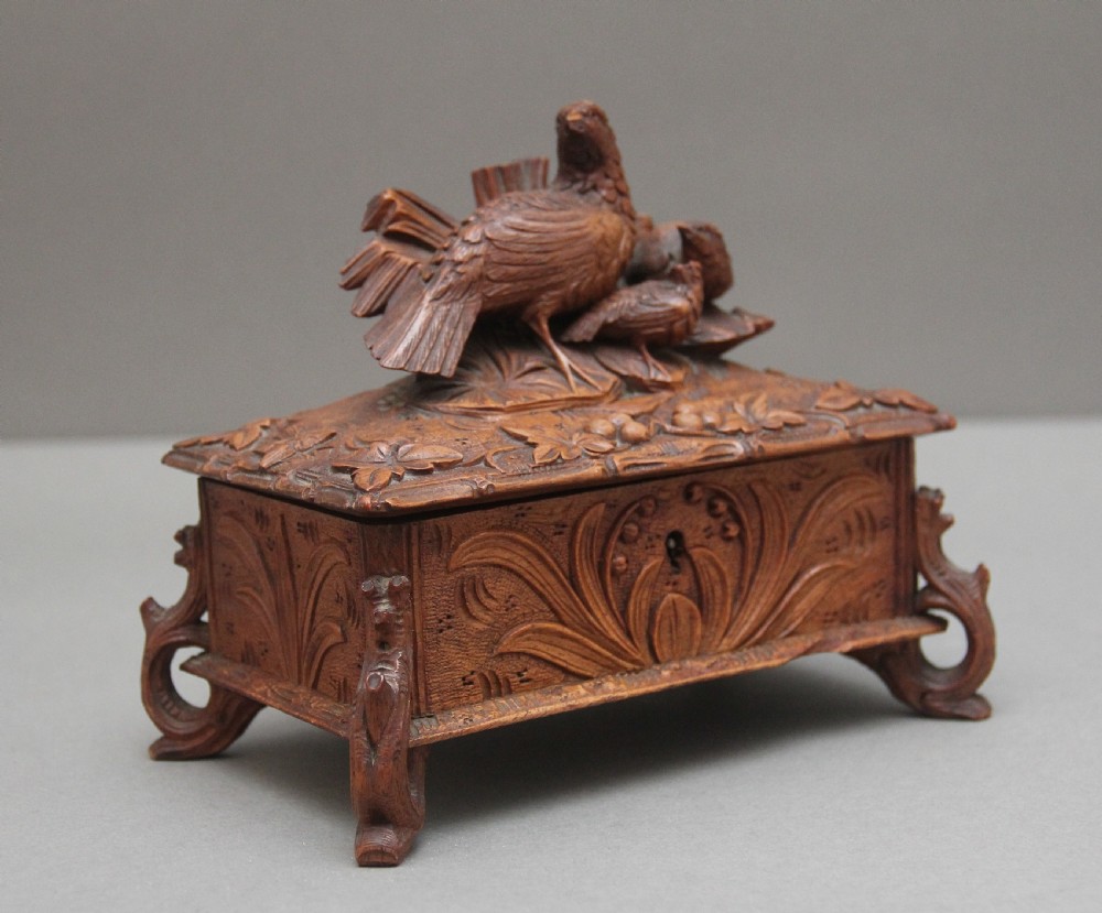 A 19th-century carved walnut casket featuring a game bird figure sculpted on the hinged lid and foliate scroll feet.