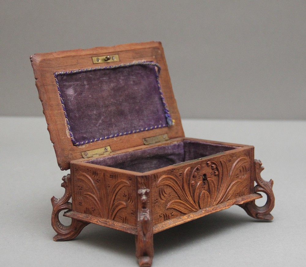 A 19th-century carved walnut casket featuring a game bird figure sculpted on the hinged lid and foliate scroll feet. View II