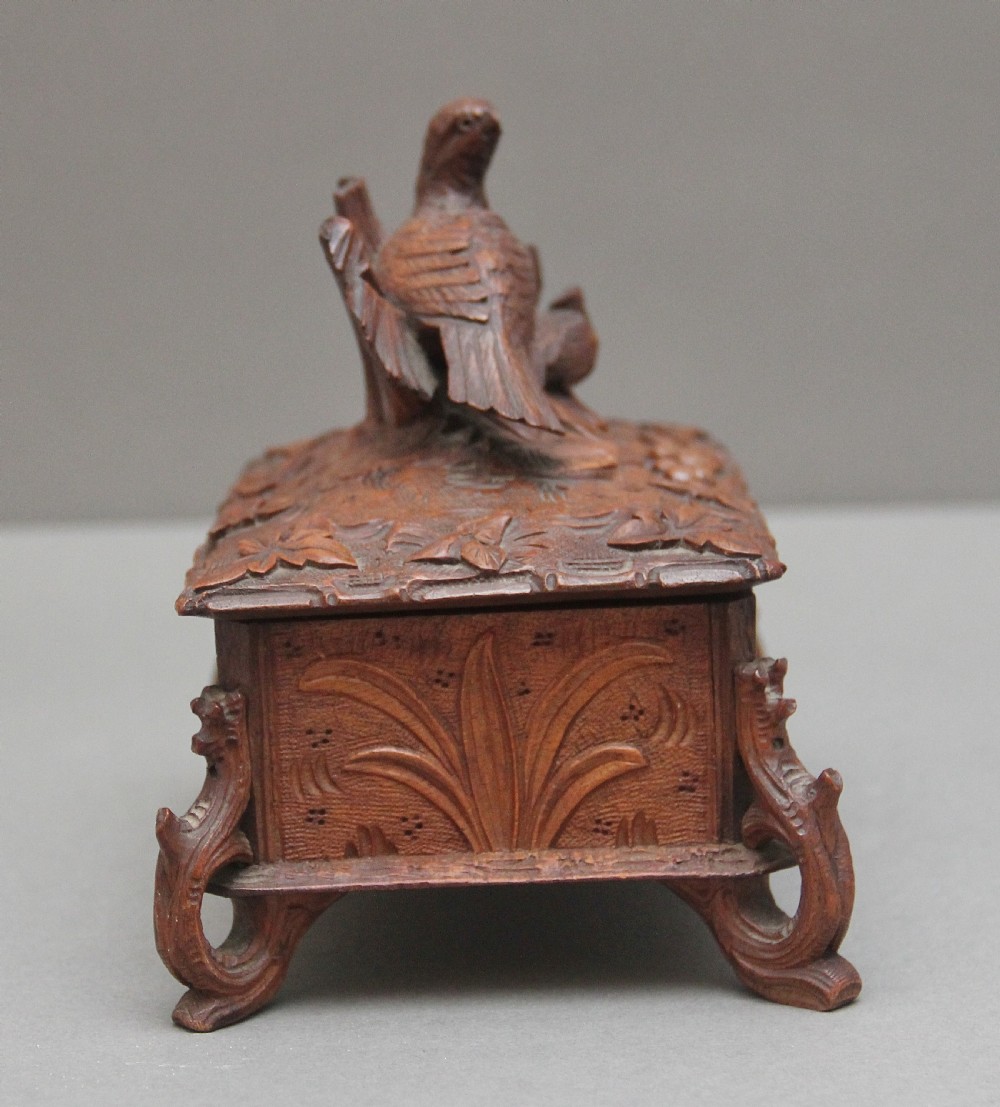 A 19th-century carved walnut casket featuring a game bird figure sculpted on the hinged lid and foliate scroll feet. View III