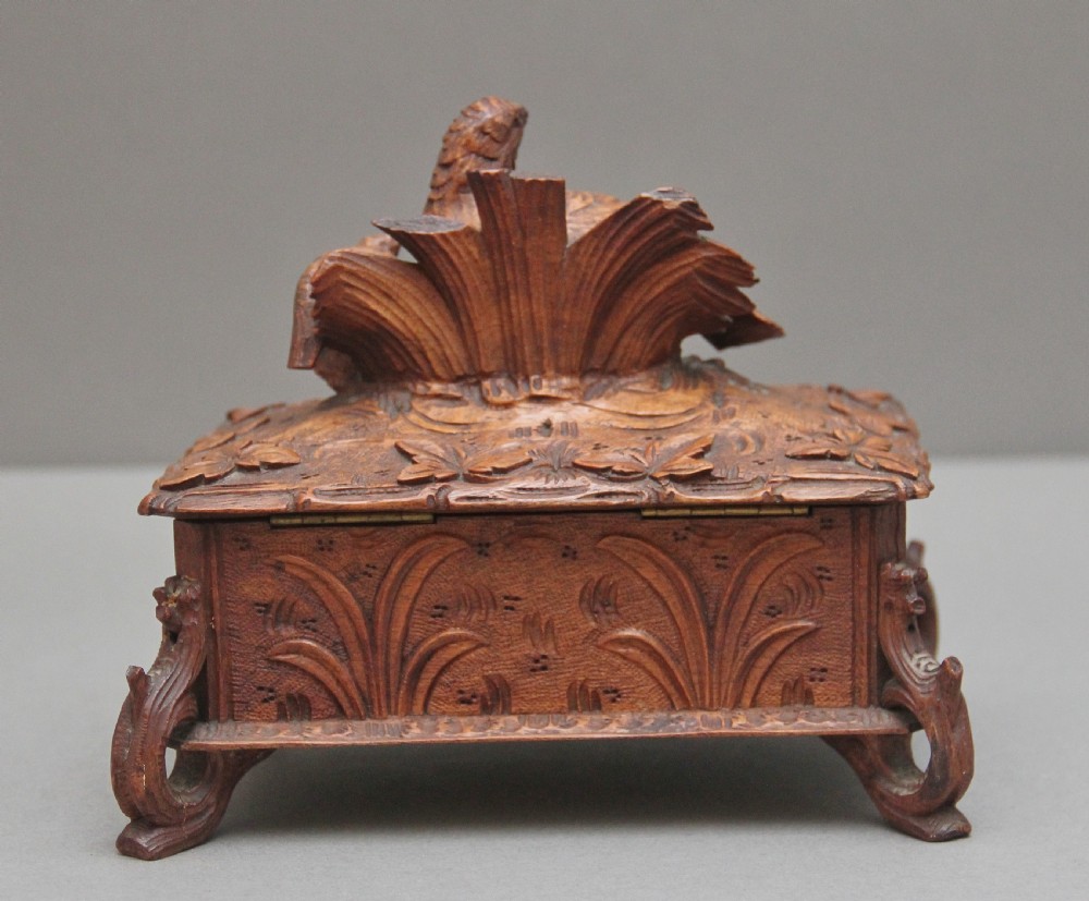 A 19th-century carved walnut casket featuring a game bird figure sculpted on the hinged lid and foliate scroll feet. View V