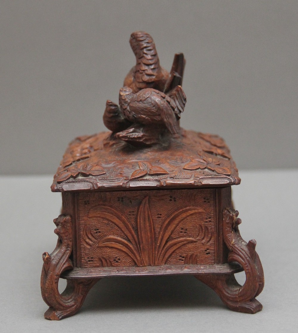 A 19th-century carved walnut casket featuring a game bird figure sculpted on the hinged lid and foliate scroll feet. View VII