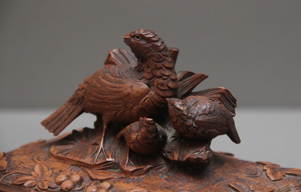 A 19th-century carved walnut casket featuring a game bird figure sculpted on the hinged lid and foliate scroll feet. View X