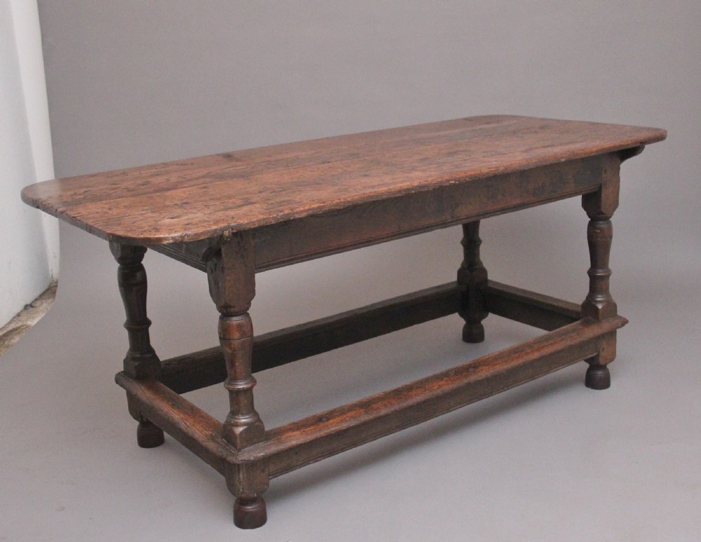 A 17th-century oak refectory table featuring a plank top, turned legs, and a perimeter box stretcher base.
