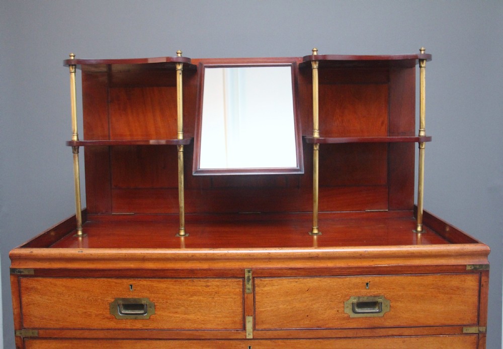 A 19th-century mahogany campaign chest of drawers featuring brass corner brackets, flush brass handles, turned feet, and an upper shelf superstructure with a central mirror. View II
