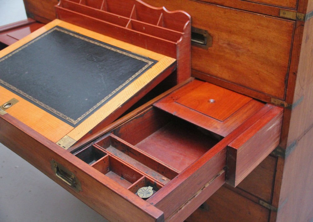 A 19th-century mahogany campaign chest of drawers featuring brass corner brackets, flush brass handles, turned feet, and an upper shelf superstructure with a central mirror. View VI
