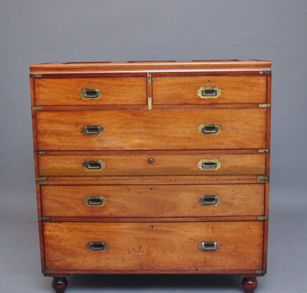 A 19th-century mahogany campaign chest of drawers featuring brass corner brackets, flush brass handles, turned feet, and an upper shelf superstructure with a central mirror. View XI