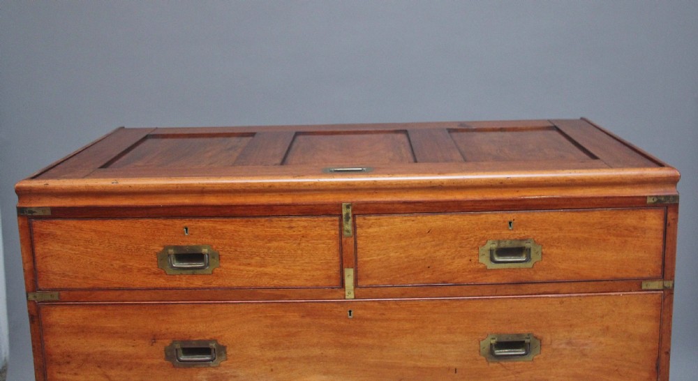 A 19th-century mahogany campaign chest of drawers featuring brass corner brackets, flush brass handles, turned feet, and an upper shelf superstructure with a central mirror. View XII