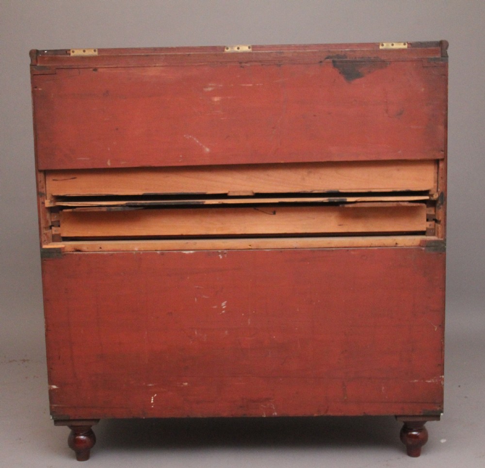 A 19th-century mahogany campaign chest of drawers featuring brass corner brackets, flush brass handles, turned feet, and an upper shelf superstructure with a central mirror. View XIV