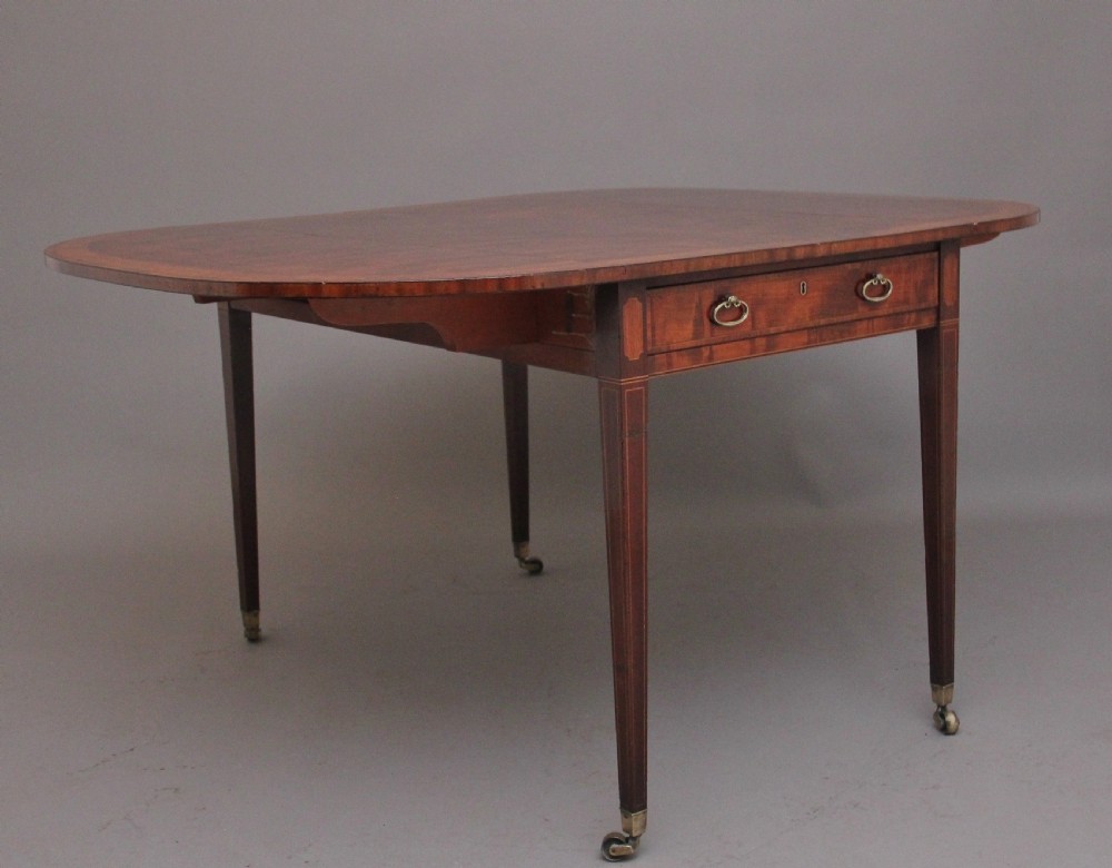 An early 19th-century inlaid mahogany Pembroke table with rounded drop leaves, a single frieze drawer, tapered legs, and brass castors. View II