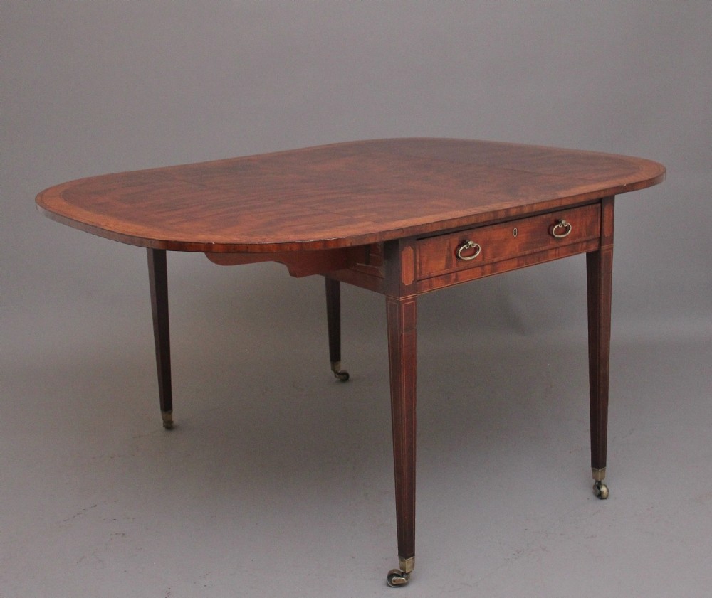 An early 19th-century inlaid mahogany Pembroke table with rounded drop leaves, a single frieze drawer, tapered legs, and brass castors. View III