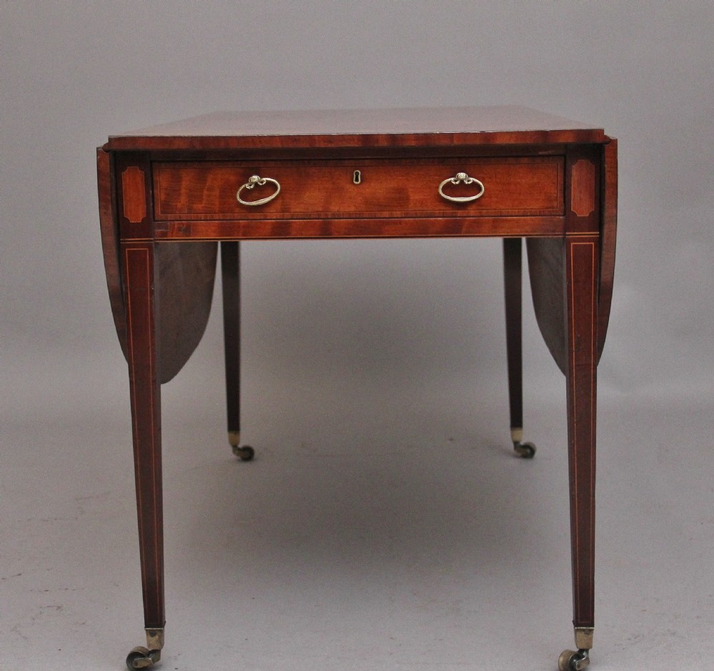 An early 19th-century inlaid mahogany Pembroke table with rounded drop leaves, a single frieze drawer, tapered legs, and brass castors. View IV