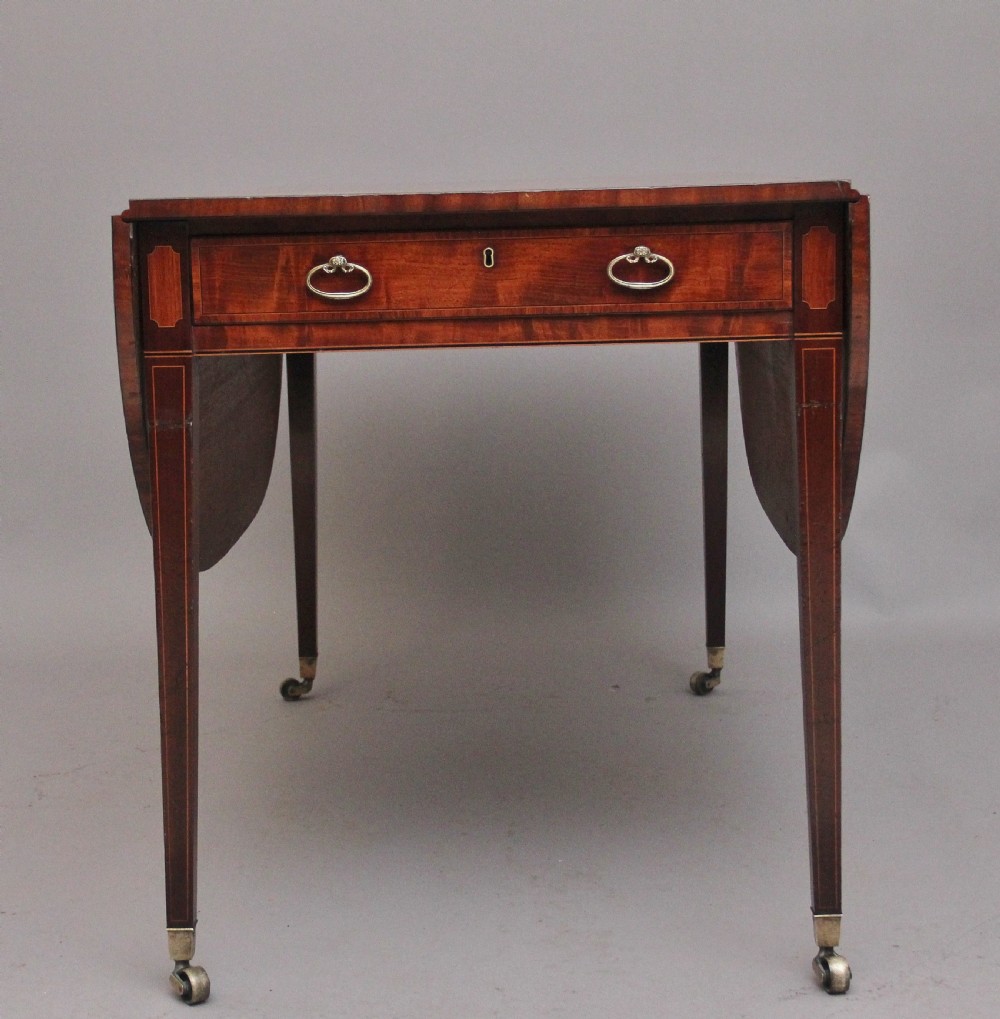 An early 19th-century inlaid mahogany Pembroke table with rounded drop leaves, a single frieze drawer, tapered legs, and brass castors. View VI
