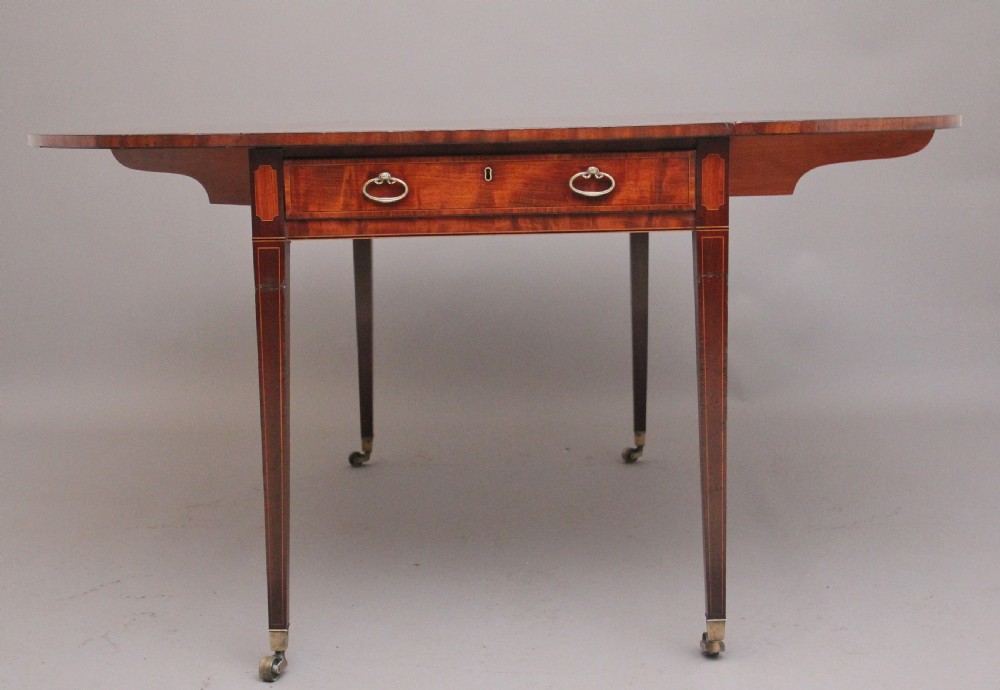 An early 19th-century inlaid mahogany Pembroke table with rounded drop leaves, a single frieze drawer, tapered legs, and brass castors. View VII