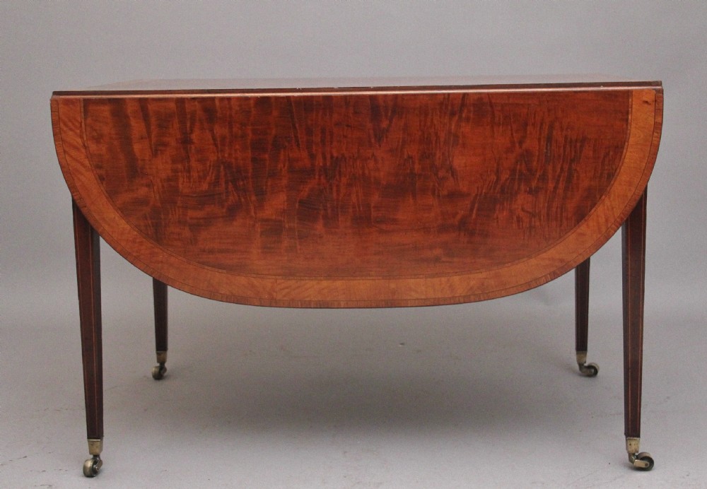 An early 19th-century inlaid mahogany Pembroke table with rounded drop leaves, a single frieze drawer, tapered legs, and brass castors. View IX