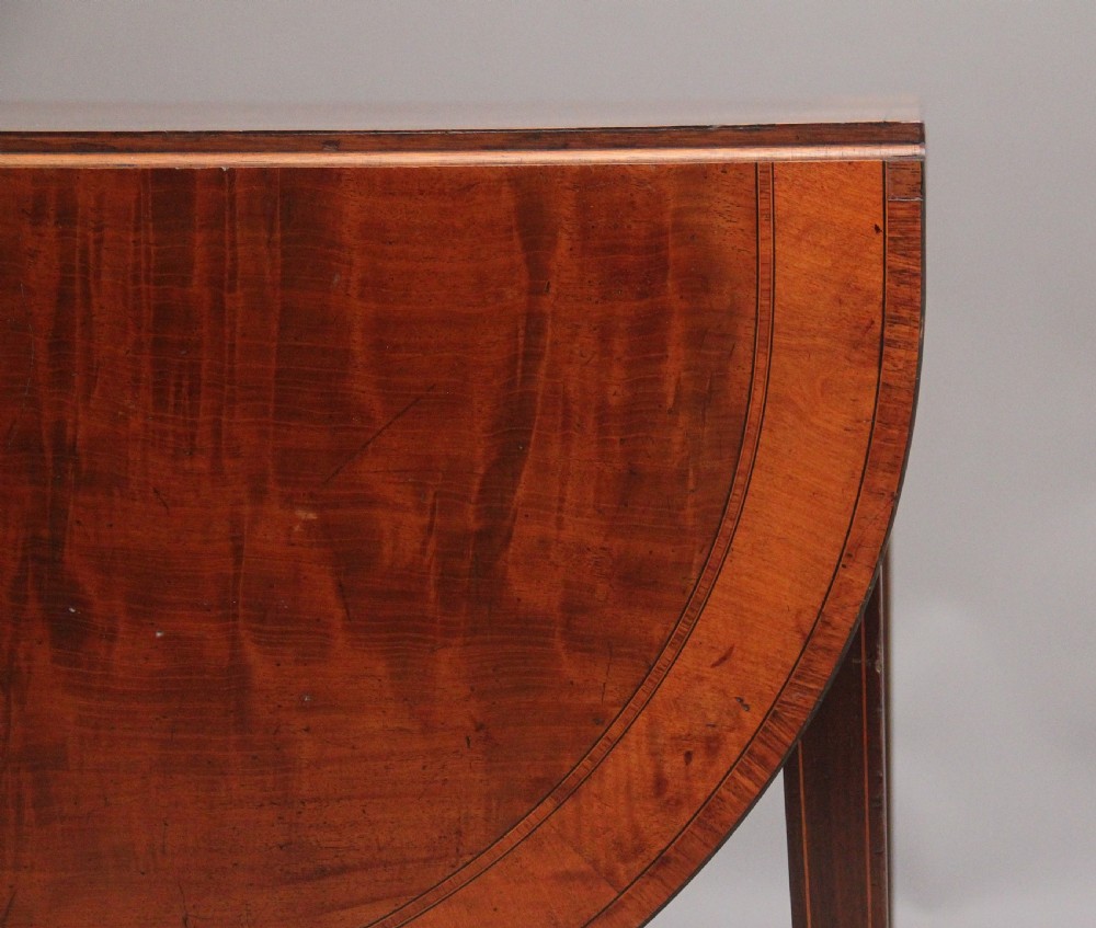 An early 19th-century inlaid mahogany Pembroke table with rounded drop leaves, a single frieze drawer, tapered legs, and brass castors. View XIV