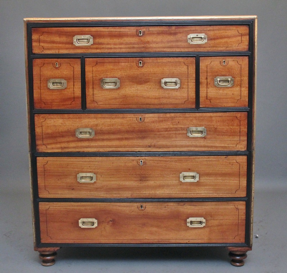 A 19th-century camphor wood military campaign chest featuring brass corner mounts, flush handles, ebonised drawer surrounds, and turned feet.