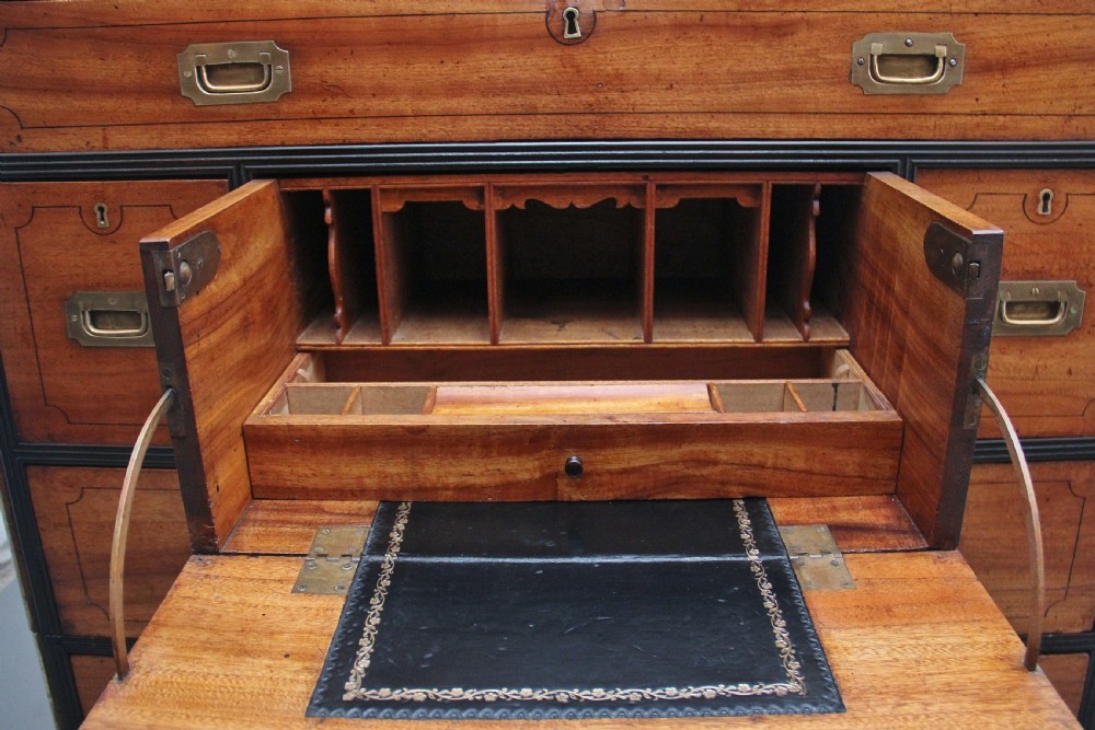 A 19th-century camphor wood military campaign chest featuring brass corner mounts, flush handles, ebonised drawer surrounds, and turned feet. View VI