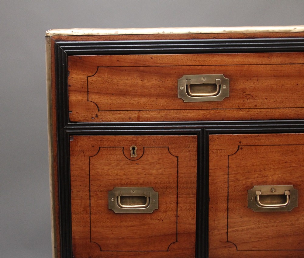A 19th-century camphor wood military campaign chest featuring brass corner mounts, flush handles, ebonised drawer surrounds, and turned feet. View VIII