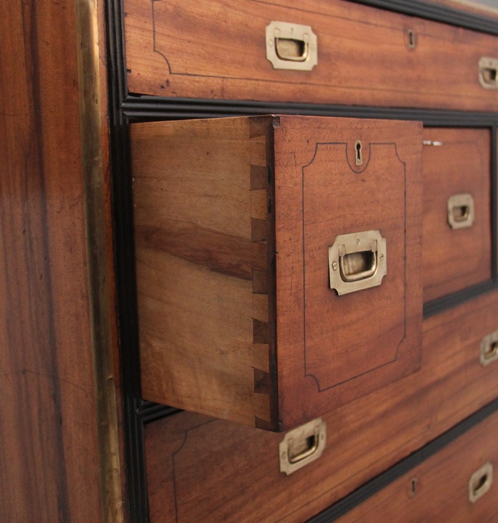 A 19th-century camphor wood military campaign chest featuring brass corner mounts, flush handles, ebonised drawer surrounds, and turned feet. View XI