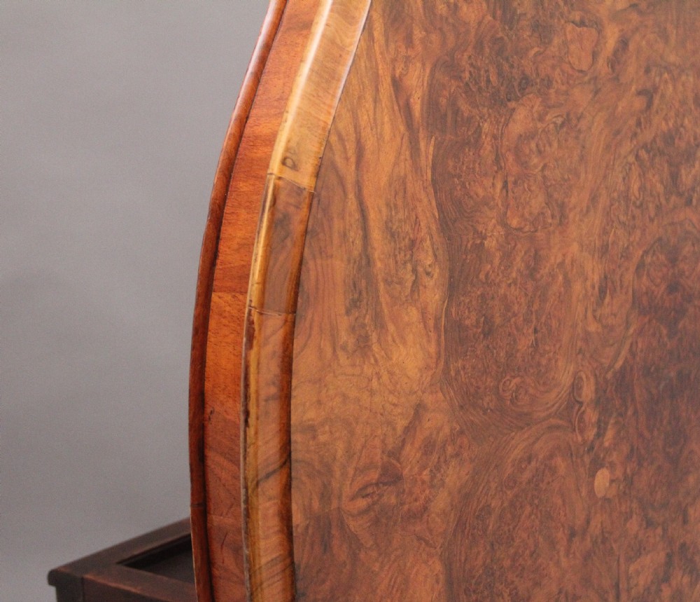 A 19th-century Victorian burr walnut centre table with a shaped, highly figured tilt-top top, raised on a carved pedestal with four cabriole legs on brass castors. View V