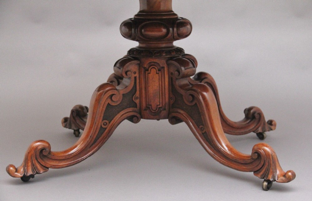 A 19th-century Victorian burr walnut centre table with a shaped, highly figured tilt-top top, raised on a carved pedestal with four cabriole legs on brass castors. View VIII