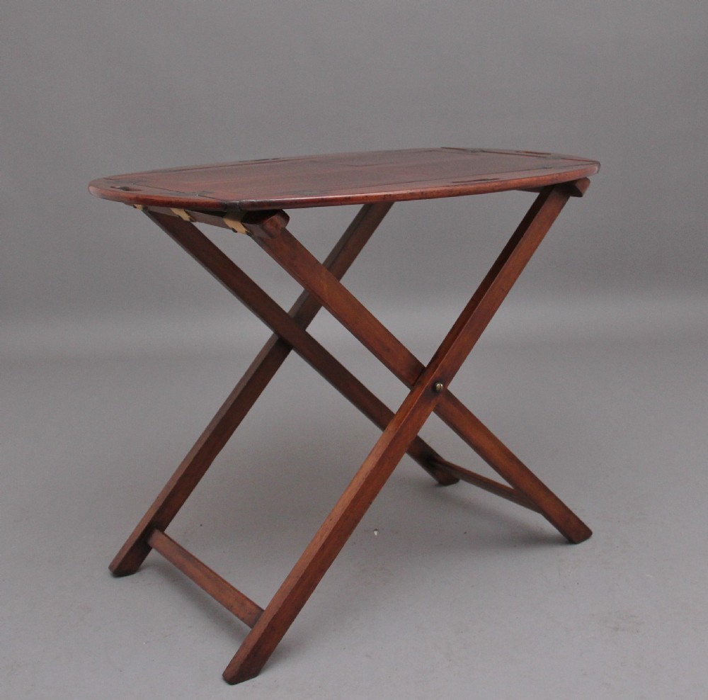 A 19th-century mahogany butler tray featuring shaped gallery sides with cutout handles resting upon a collapsible X-frame stand with webbing straps. View II