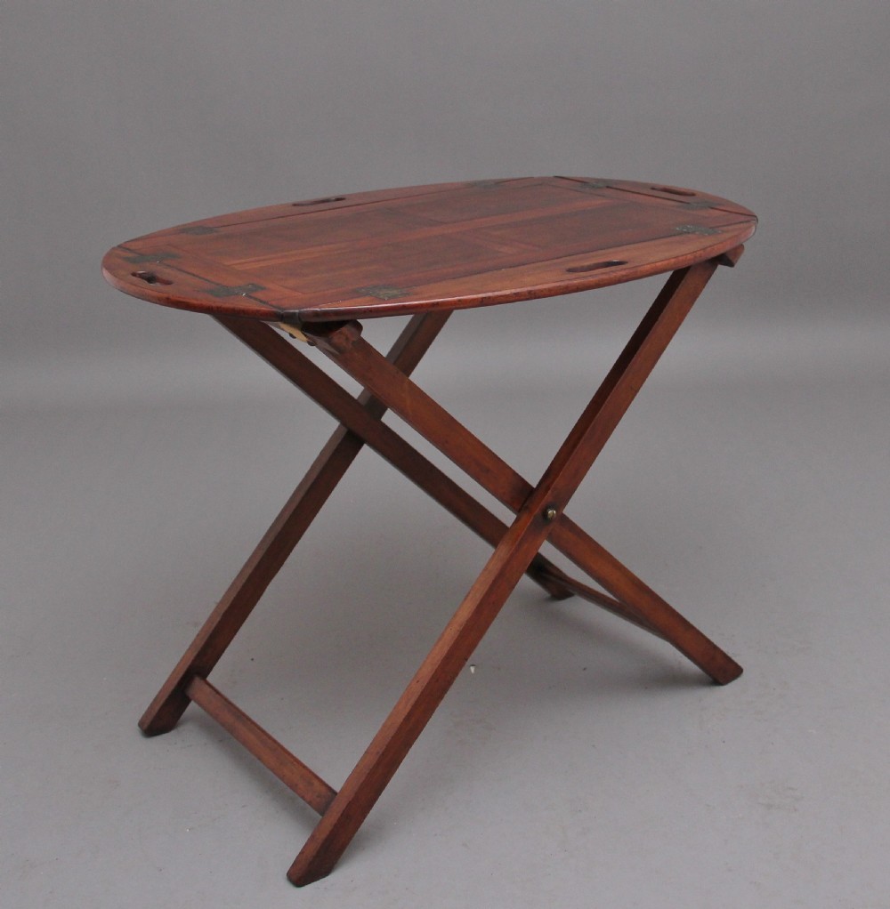 A 19th-century mahogany butler tray featuring shaped gallery sides with cutout handles resting upon a collapsible X-frame stand with webbing straps. View III