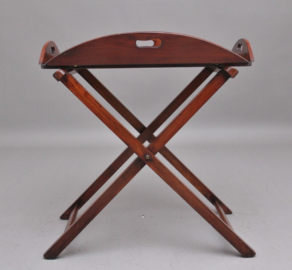 A 19th-century mahogany butler tray featuring shaped gallery sides with cutout handles resting upon a collapsible X-frame stand with webbing straps. View IX