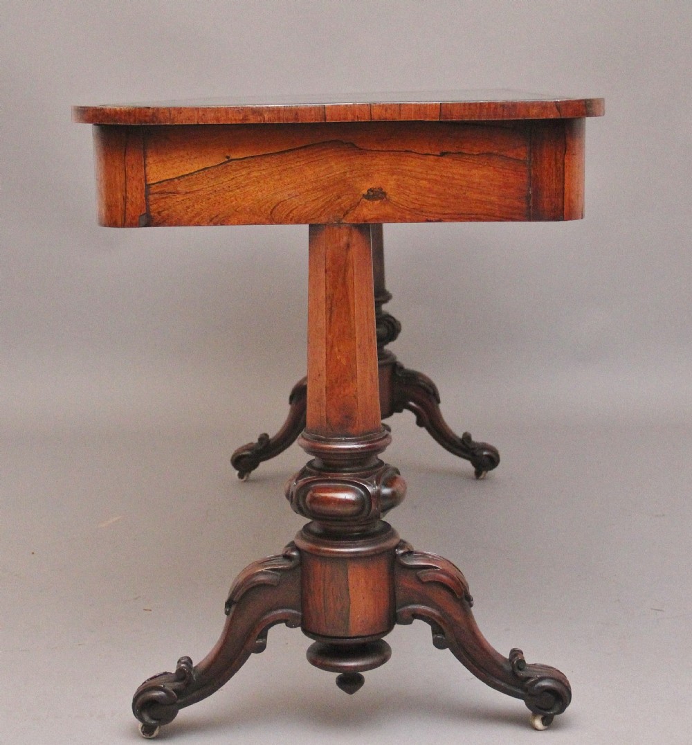 A nineteenth-century dark rosewood library table featuring two frieze drawers, turned trestle supports, a central stretcher, and scroll feet on brass castors. View VII