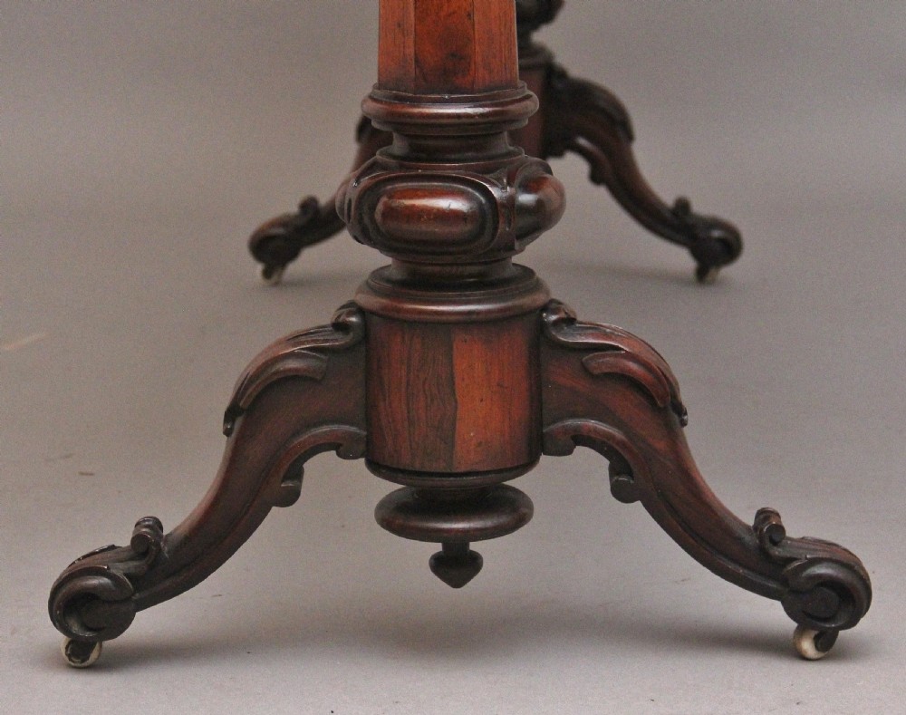 A nineteenth-century dark rosewood library table featuring two frieze drawers, turned trestle supports, a central stretcher, and scroll feet on brass castors. View X