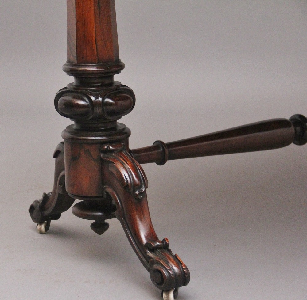 A nineteenth-century dark rosewood library table featuring two frieze drawers, turned trestle supports, a central stretcher, and scroll feet on brass castors. View XI