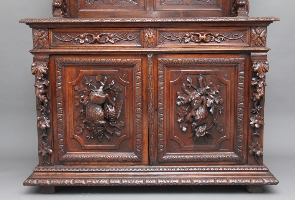 A 19th-century dark oak two-tiered buffet featuring intricate hand-carved reliefs of game, foliage, and a prominent stag head cresting. View III