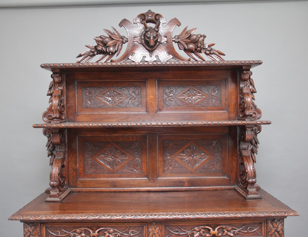 A 19th-century dark oak two-tiered buffet featuring intricate hand-carved reliefs of game, foliage, and a prominent stag head cresting. View VII