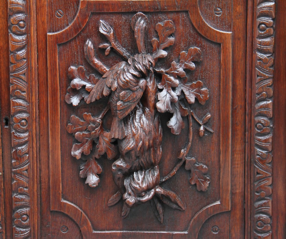 A 19th-century dark oak two-tiered buffet featuring intricate hand-carved reliefs of game, foliage, and a prominent stag head cresting. View XI