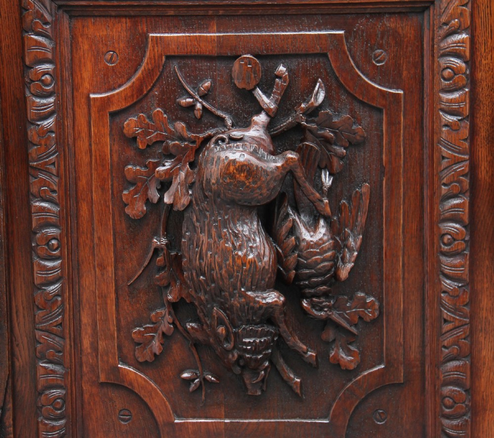 A 19th-century dark oak two-tiered buffet featuring intricate hand-carved reliefs of game, foliage, and a prominent stag head cresting. View XII