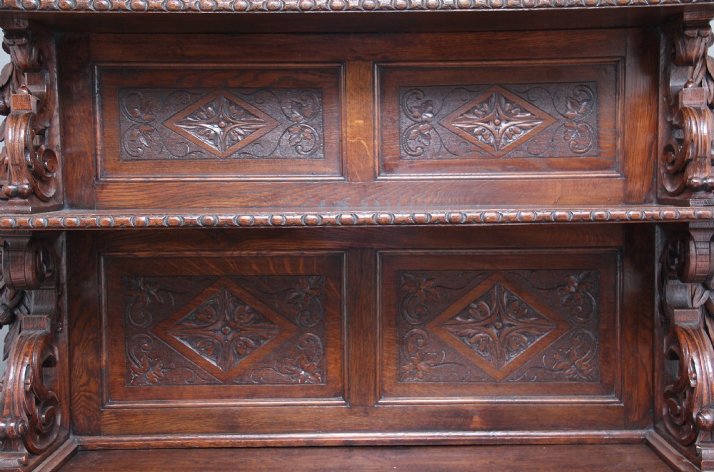 A 19th-century dark oak two-tiered buffet featuring intricate hand-carved reliefs of game, foliage, and a prominent stag head cresting. View XIII